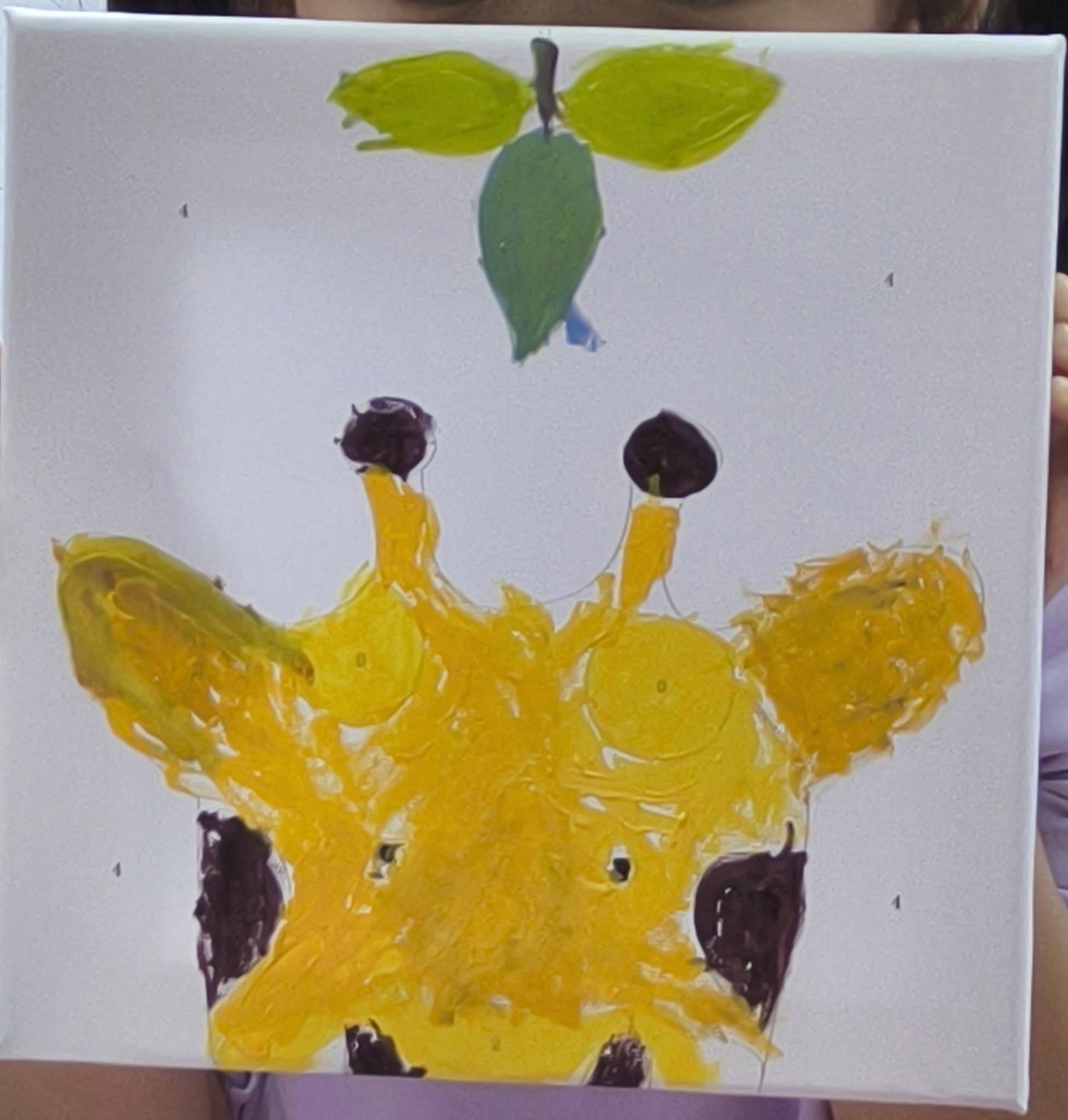 Hand-painted canvas of a yellow giraffe with brown spots from Play and Unite at Canberra Plaza